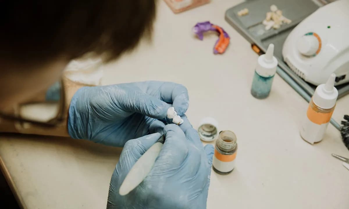 Eldivenli ellerle dental modele ayrıntılı işlem yapan teknisyen
