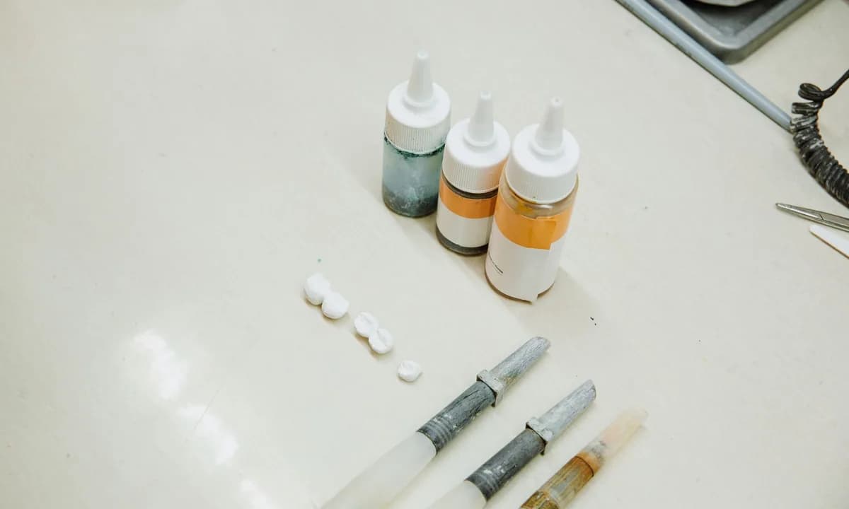 Laboratuvar masasında küçük dental kronlar, şişeler ve el aletleri