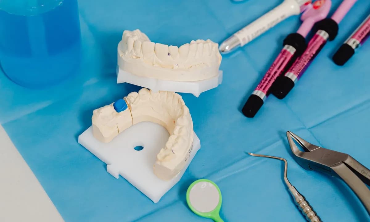 Mavi masa üzerinde dental modeller, malzeme tüpleri ve el aletleri